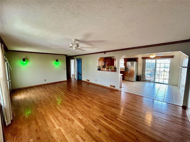 502 Mcclaren Way, Dixon, MO 65459 - unfurnished living room featuring ceiling fan, light wood-style flooring, ornamental molding, a textured ceiling, and arched walkways