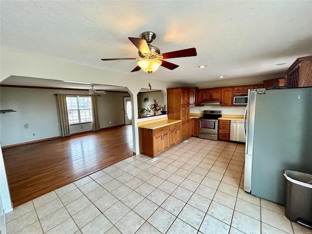 502 Mcclaren Way, Dixon, MO 65459 - kitchen with appliances with stainless steel finishes, light tile patterned floors, a ceiling fan, open floor plan, and light countertops