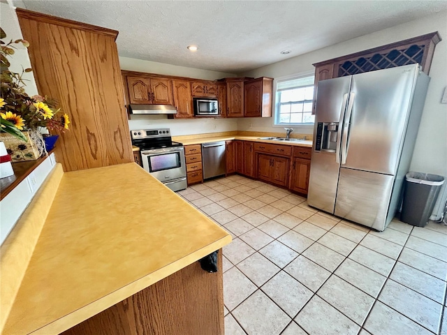 502 Mcclaren Way, Dixon, MO 65459 - kitchen with appliances with stainless steel finishes, under cabinet range hood, light countertops, a sink, and light tile patterned flooring