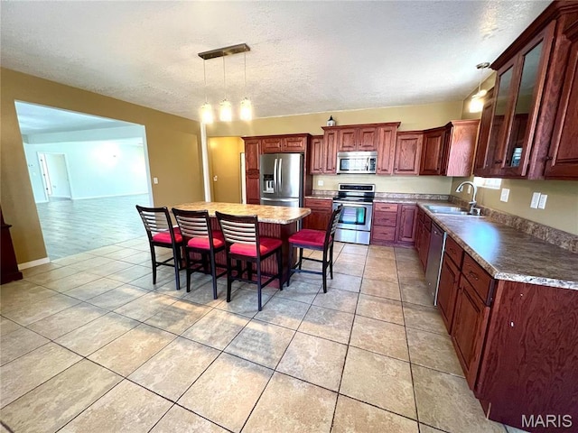 792 County Road 466, Poplar Bluff, MO 63901 - kitchen featuring appliances with stainless steel finishes, a sink, pendant lighting, light tile patterned floors, and a textured ceiling