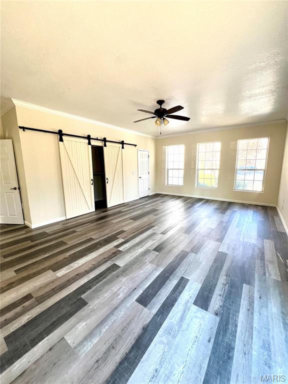 792 County Road 466, Poplar Bluff, MO 63901 - spare room with a barn door, healthy amount of natural light, wood finished floors, ceiling fan, and ornamental molding