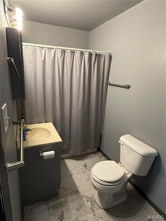 bathroom featuring toilet, vanity, marble look tile flooring, and curtained shower