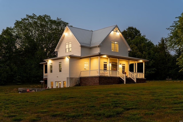back of house with a lawn, metal roof, and a porch