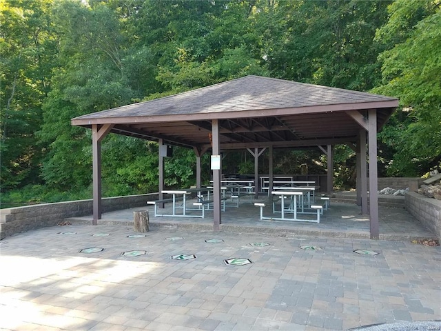 view of community with a gazebo, a view of trees, and a patio area
