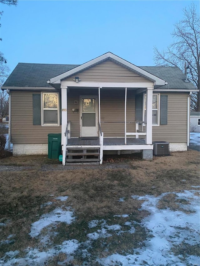view of front of home with covered porch, a shingled roof, and cooling unit