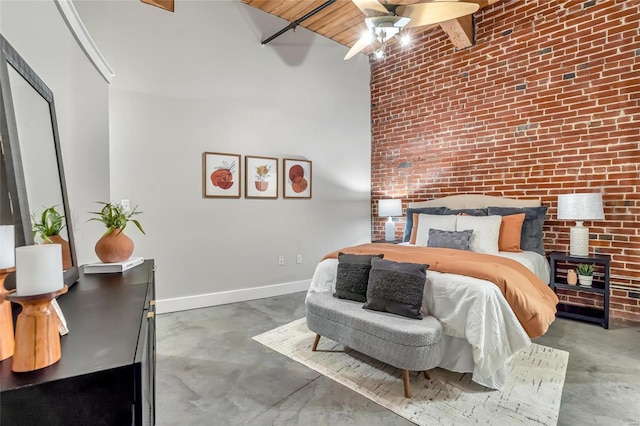 bedroom with concrete floors, brick wall, baseboards, a ceiling fan, and a towering ceiling