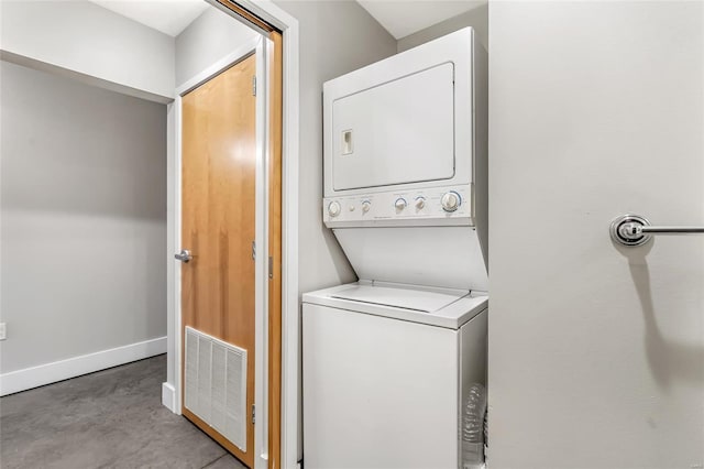 clothes washing area with estacked washer and dryer and baseboards