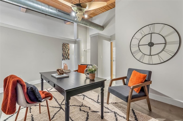 office space featuring baseboards, a high ceiling, wooden ceiling, and a ceiling fan