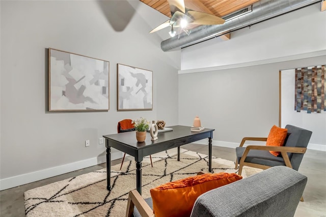 office space featuring concrete floors, a ceiling fan, baseboards, and a towering ceiling