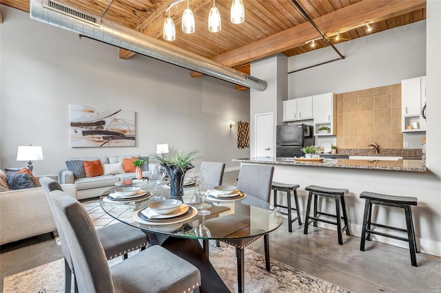 dining area featuring wood ceiling, concrete floors, beamed ceiling, and a towering ceiling
