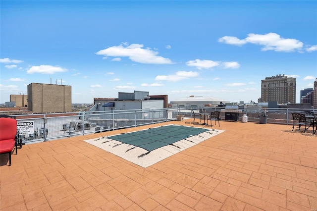view of pool featuring a patio, fence, and a view of city