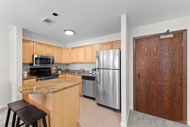 950 E Rue De La Banque Unit 110, Creve Coeur, MO 63141 - kitchen with stainless steel appliances, light brown cabinets, a sink, light stone countertops, and baseboards