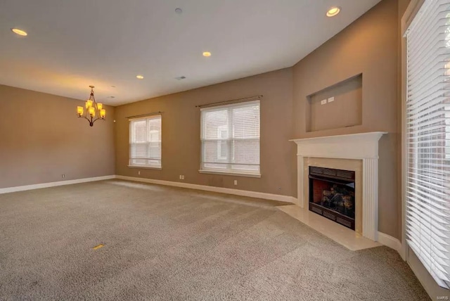 unfurnished living room with carpet, a chandelier, a fireplace with flush hearth, baseboards, and recessed lighting