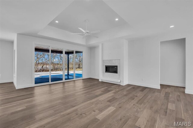 600 Legacy Dr, Waterloo, IL 62298 - unfurnished living room featuring a tray ceiling, baseboards, a ceiling fan, wood finished floors, and recessed lighting