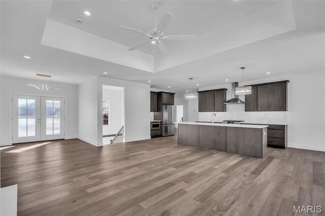 600 Legacy Dr, Waterloo, IL 62298 - kitchen featuring wall chimney exhaust hood, open floor plan, freestanding refrigerator, tasteful backsplash, and wood finished floors