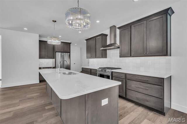 600 Legacy Dr, Waterloo, IL 62298 - kitchen featuring wall chimney range hood, premium appliances, a sink, a chandelier, and baseboards