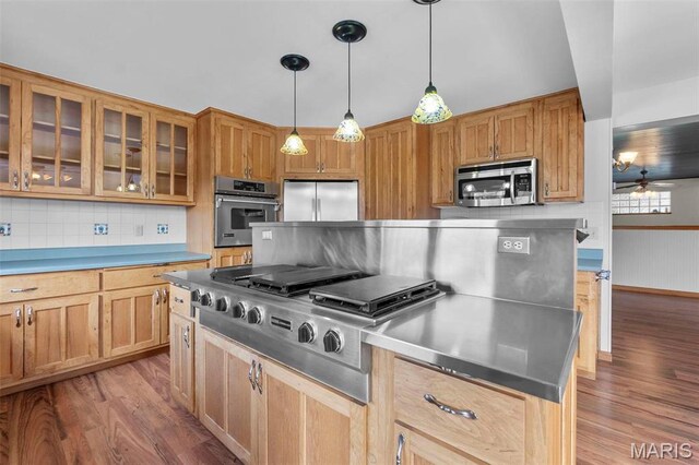 520 Christopher Dr, Perryville, MO 63775 - kitchen with appliances with stainless steel finishes, wood finished floors, glass insert cabinets, pendant lighting, and decorative backsplash