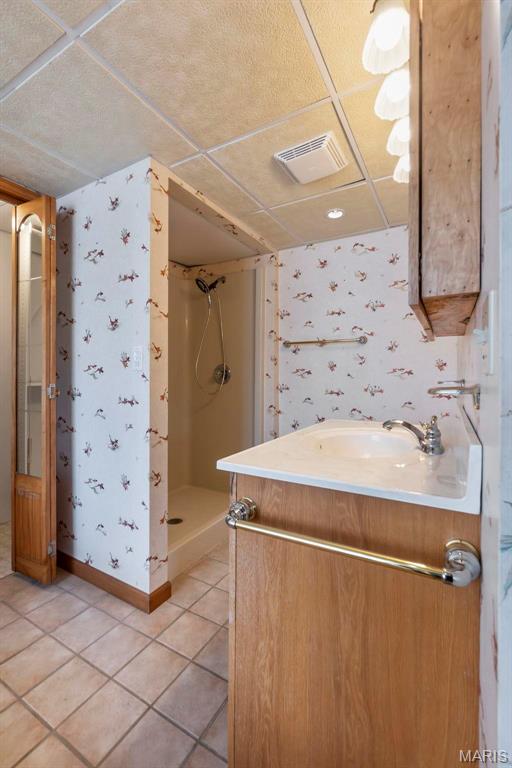 520 Christopher Dr, Perryville, MO 63775 - bathroom featuring wallpapered walls, a shower stall, a drop ceiling, vanity, and tile patterned floors