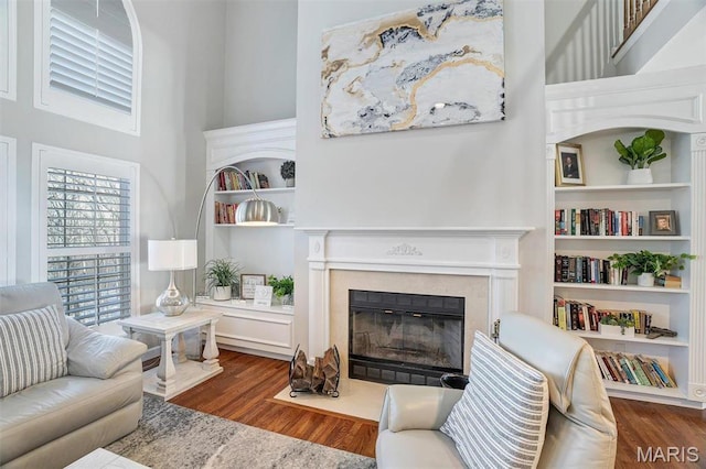 997 Sheffield Forest Ct, Wildwood, MO 63021 - living room featuring wood finished floors, a fireplace with flush hearth, a towering ceiling, and built in shelves
