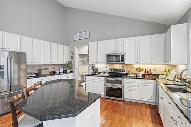 997 Sheffield Forest Ct, Wildwood, MO 63021 - kitchen featuring stainless steel appliances, high vaulted ceiling, a sink, backsplash, and white cabinets
