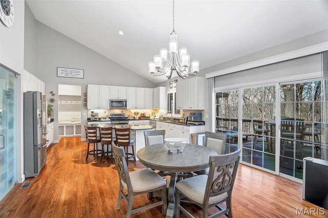 997 Sheffield Forest Ct, Wildwood, MO 63021 - dining area with a chandelier, high vaulted ceiling, and light wood finished floors