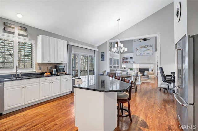 997 Sheffield Forest Ct, Wildwood, MO 63021 - kitchen with stainless steel appliances, high vaulted ceiling, a chandelier, a breakfast bar area, and white cabinetry