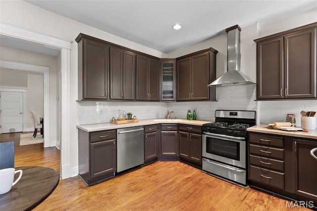 2811 Shenandoah Ave, Saint Louis, MO 63104 - kitchen with appliances with stainless steel finishes, wall chimney range hood, light countertops, light wood-type flooring, and tasteful backsplash