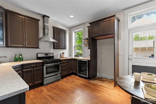 2811 Shenandoah Ave, Saint Louis, MO 63104 - kitchen with beverage cooler, gas stove, wall chimney exhaust hood, light countertops, and decorative backsplash
