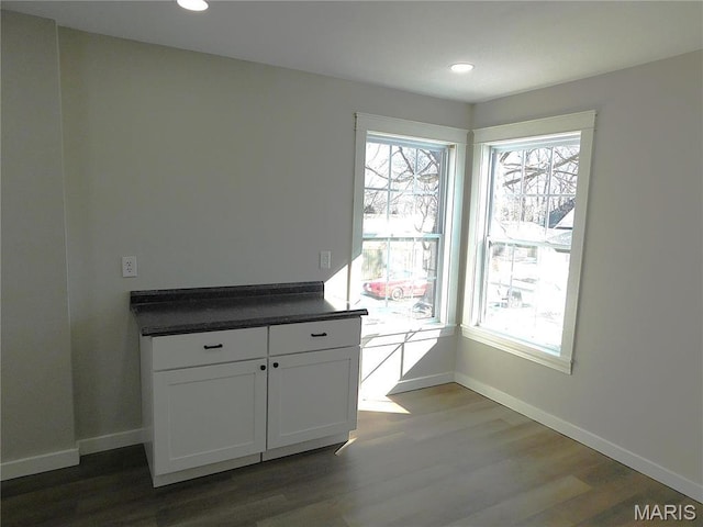 unfurnished dining area featuring dark wood-style floors, baseboards, and recessed lighting