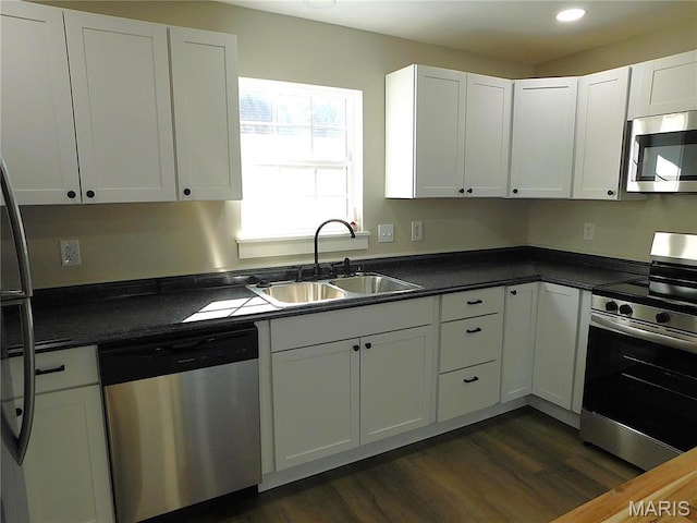 kitchen with stainless steel appliances, a sink, dark wood-type flooring, dark countertops, and recessed lighting