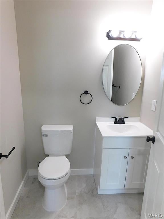 half bath featuring toilet, baseboards, and vanity