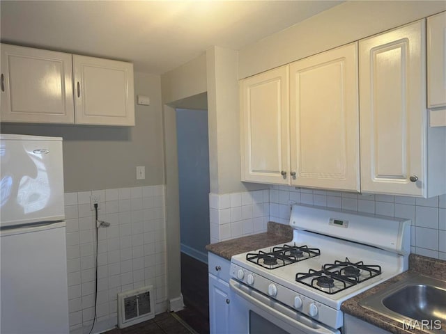 9100 Gedde Ave, Saint Louis, MO 63134 - kitchen with white appliances, white cabinets, tile walls, dark countertops, and a sink