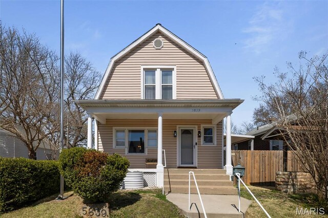 5839 W Park Ave, Saint Louis, MO 63110 - colonial inspired home featuring a gambrel roof, fence, and covered porch