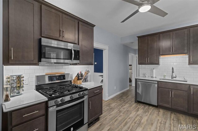 5839 W Park Ave, Saint Louis, MO 63110 - kitchen featuring appliances with stainless steel finishes, a sink, baseboards, backsplash, and dark brown cabinets