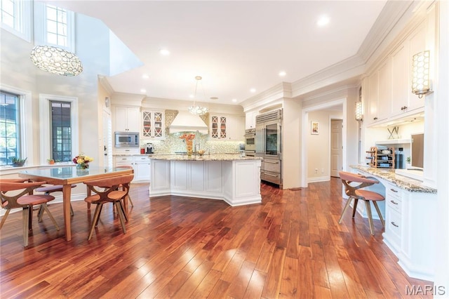 16 Holiday Ln, Saint Louis, MO 63131 - kitchen with stainless steel microwave, a chandelier, a center island, glass insert cabinets, and white cabinetry