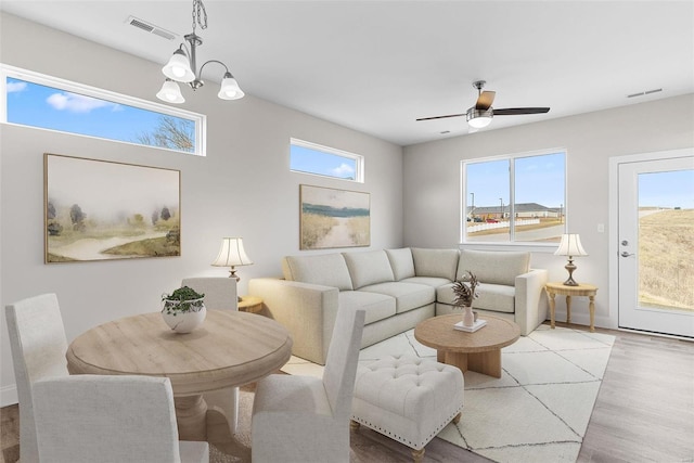living room featuring wood finished floors, a ceiling fan, baseboards, and a chandelier