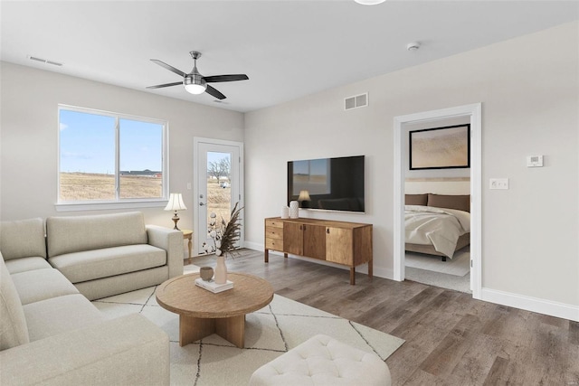 living area with wood finished floors, a ceiling fan, and baseboards