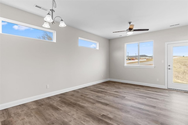 unfurnished dining area featuring healthy amount of natural light, wood finished floors, baseboards, and a chandelier