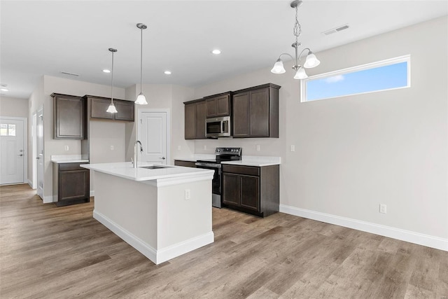 kitchen featuring stainless steel appliances, a sink, dark brown cabinets, light wood-type flooring, and baseboards