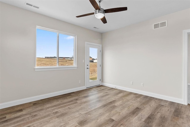 unfurnished room with wood finished floors, a ceiling fan, and baseboards