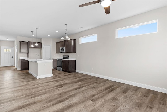 kitchen with stainless steel appliances, baseboards, open floor plan, light countertops, and recessed lighting