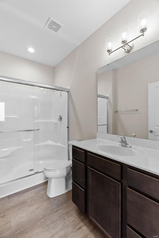 full bath with wood finished floors, a stall shower, toilet, and vanity