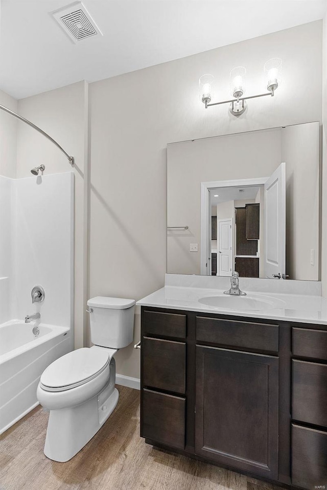 bathroom with wood finished floors, toilet, shower / tub combination, vanity, and baseboards