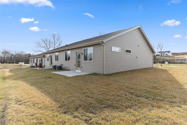 rear view of property featuring a patio, a yard, central air condition unit, and roof with shingles