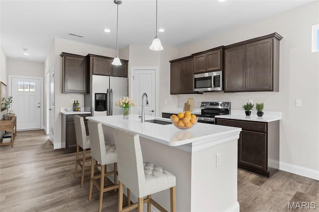 891 Walter Way, Washington, MO 63090 - kitchen featuring appliances with stainless steel finishes, a sink, dark brown cabinetry, baseboards, and light wood-type flooring