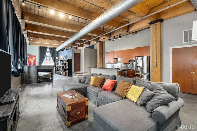 901 Washington Ave Unit 304, Saint Louis, MO 63101 - living area featuring finished concrete flooring, a wooden ceiling with exposed beams, a multi sided fireplace, and a towering ceiling
