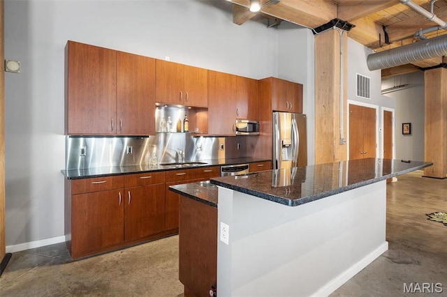901 Washington Ave Unit 304, Saint Louis, MO 63101 - kitchen featuring stainless steel appliances, a towering ceiling, finished concrete floors, brown cabinetry, and dark stone counters