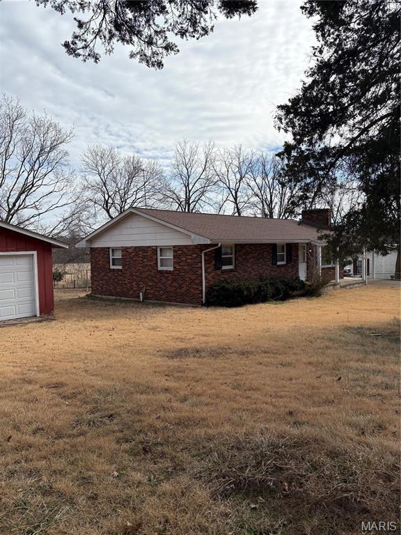 10019 Seabourne St, Belgrade, MO 63622 - view of property exterior featuring brick siding, a yard, a detached garage, and an outdoor structure