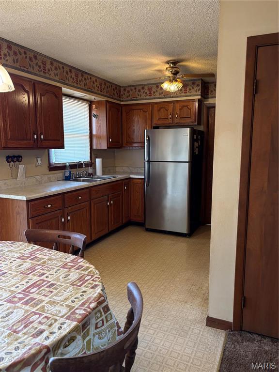 10019 Seabourne St, Belgrade, MO 63622 - kitchen with freestanding refrigerator, a sink, light countertops, a textured ceiling, and a ceiling fan