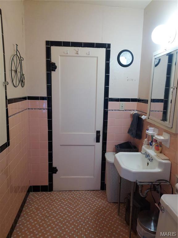 2106 Lackland Rd, Saint Louis, MO 63114 - bathroom featuring tile walls and a wainscoted wall